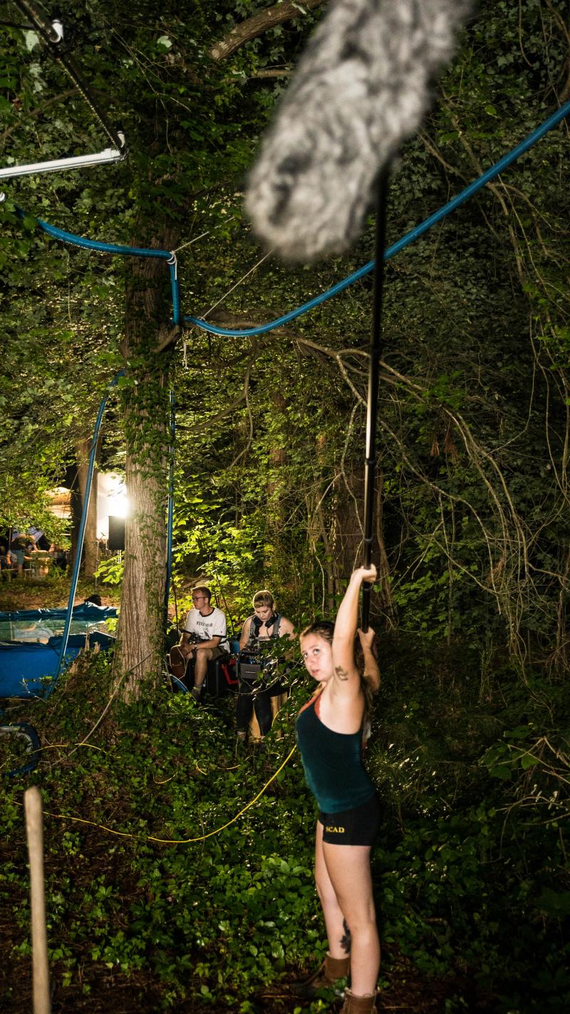 Kaylee Yacono takes one for the team, and stands under the rain rig as we go for another take.. Kaylee Yacono takes one for the team, and stands under the rain rig as we go for another take..